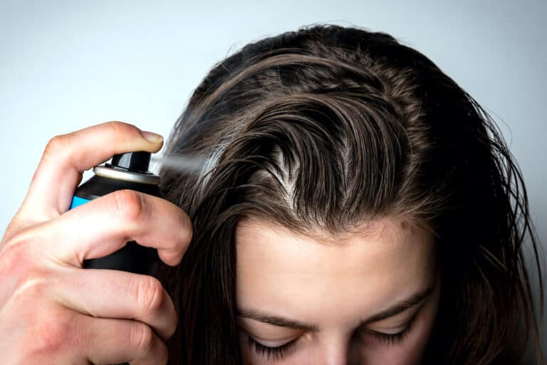 Woman Spraying Dry Shampoo Into Her Hair