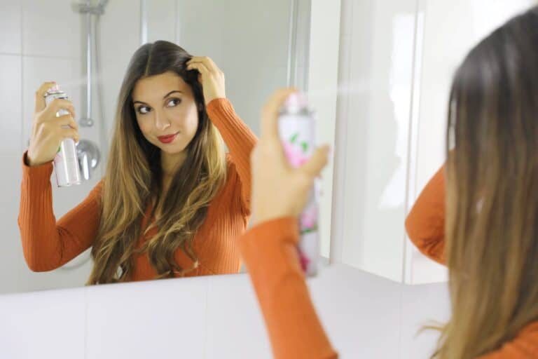 Woman Spraying Dry Shampoo In Hair