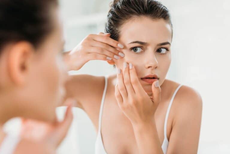 Woman Looking At Skin In Mirror