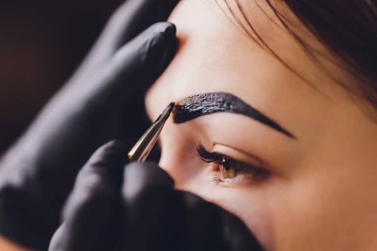 beautician/makeup artist applies paint henna on previously plucked, design, trimmed eyebrows in a beauty salon in the session correction. Professional care for face