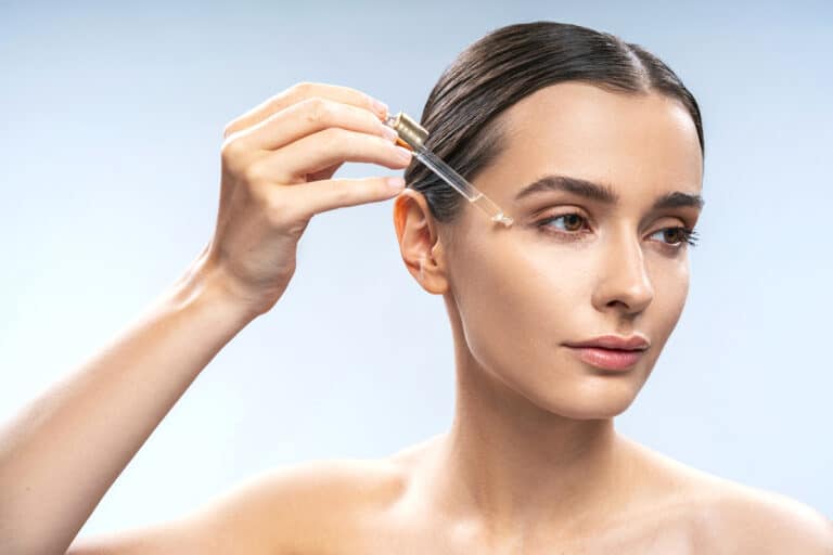 Facial oil dropper held above the under eye area