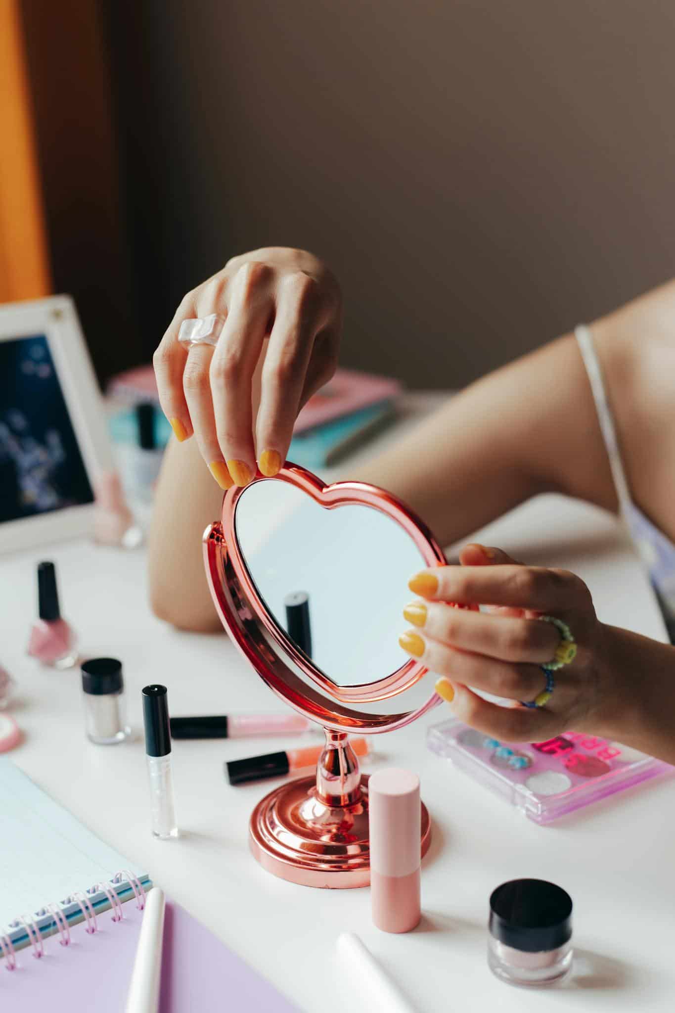 Photo by cottonbro studio - Beautygab Elegant vanity scene with cosmetics and a heart-shaped mirror in a bright setting.